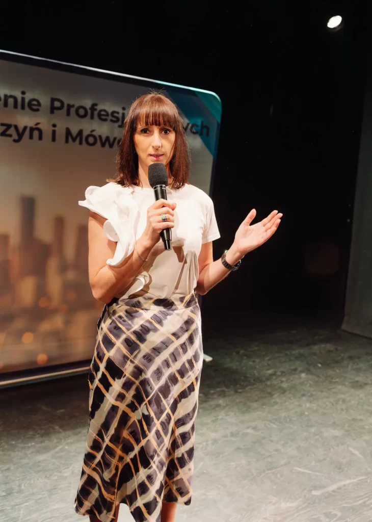 Magdalena Radomska prowadzi inspirujące wystąpienie motywacyjne dla zespołu na konferencji biznesowej.